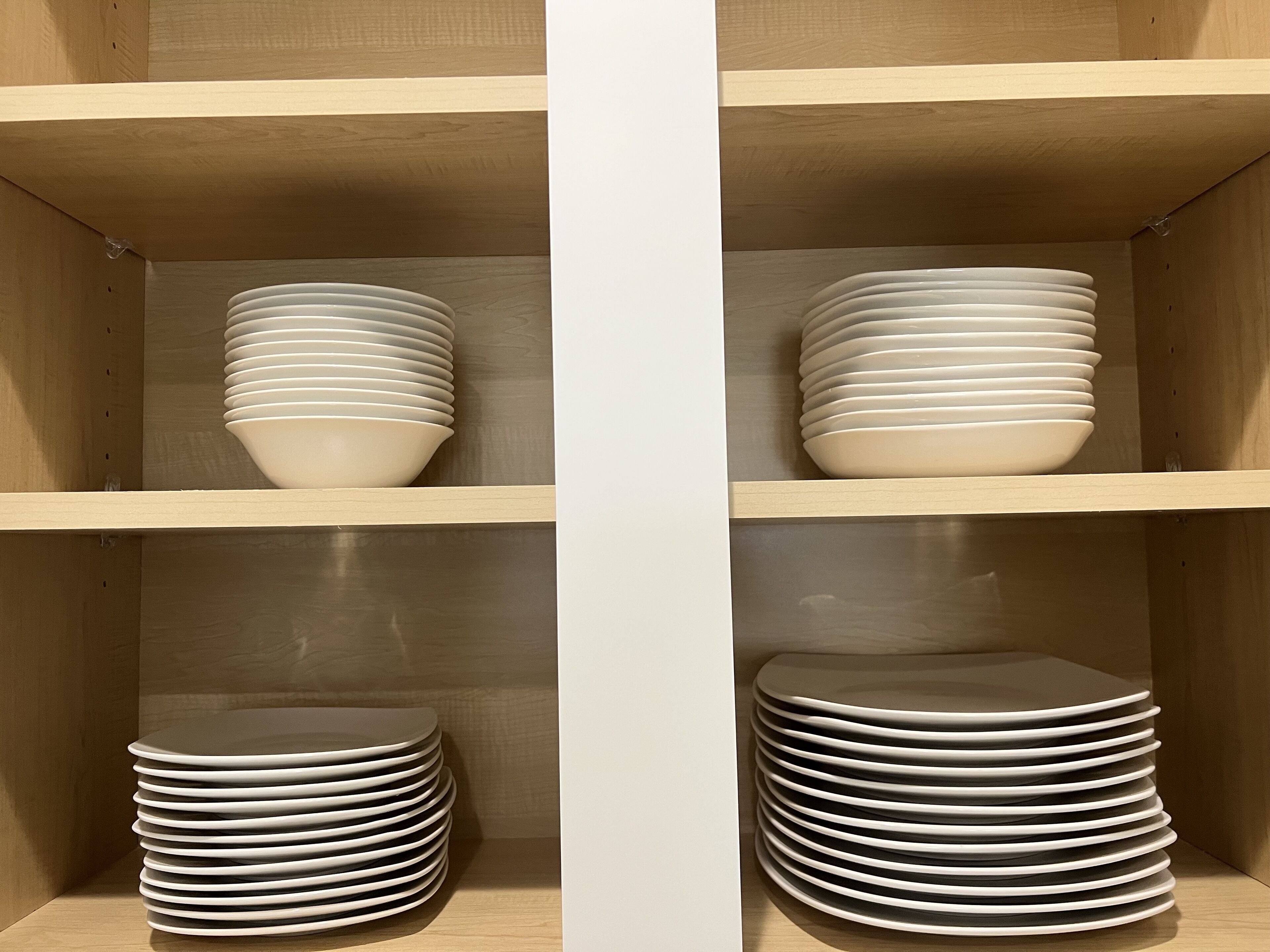 Una estantería de madera con varios cuencos y platos blancos.