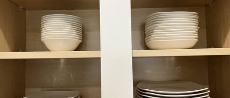 Una estantería de madera con varios cuencos y platos blancos.