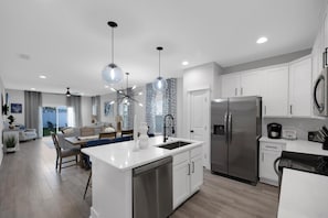 Una cocina moderna con armarios blancos, electrodomésticos de acero inoxidable y una isla central.