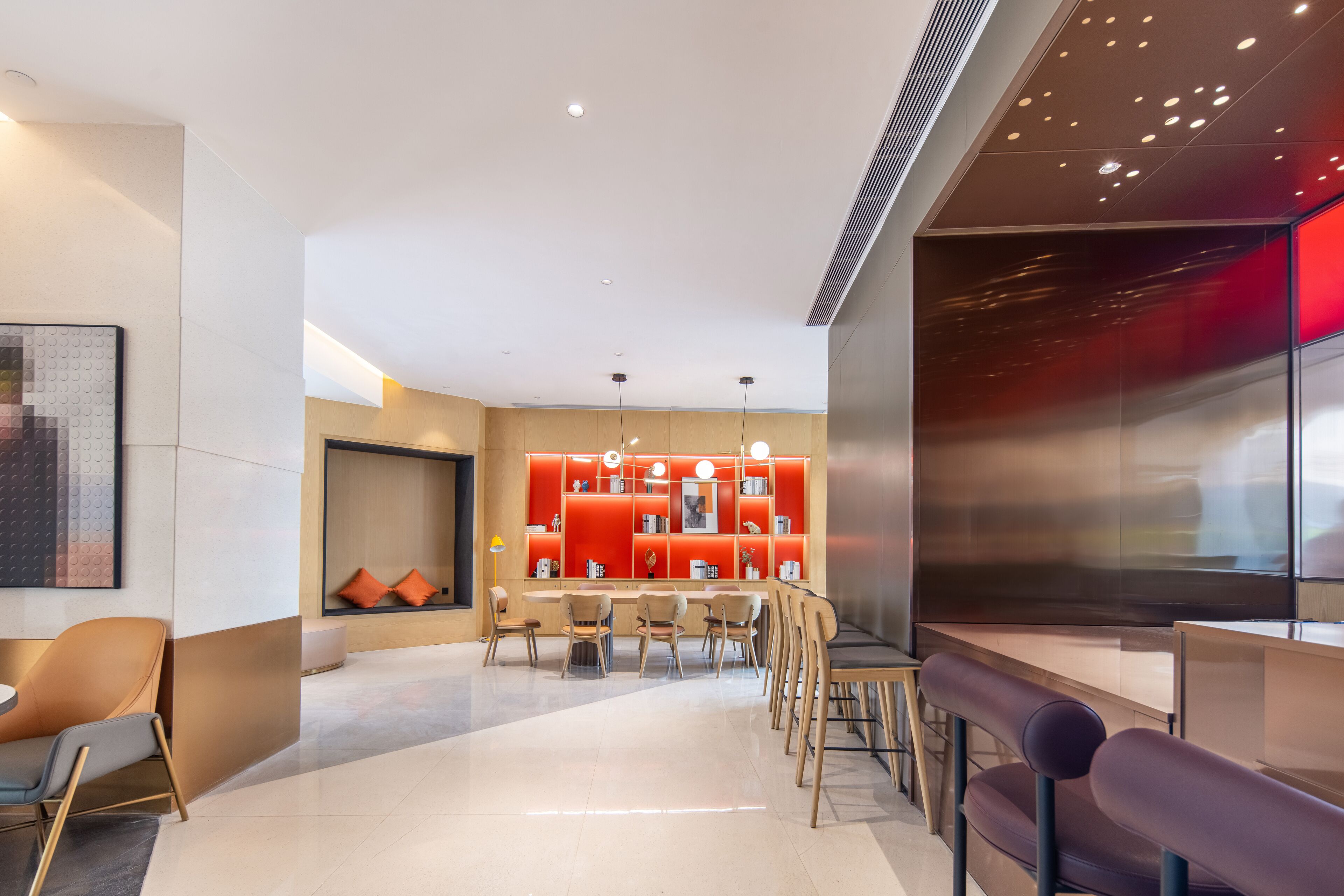 En modern hotellobby med en central sittgrupp, en röd accentvägg och en stor tv-skärm.