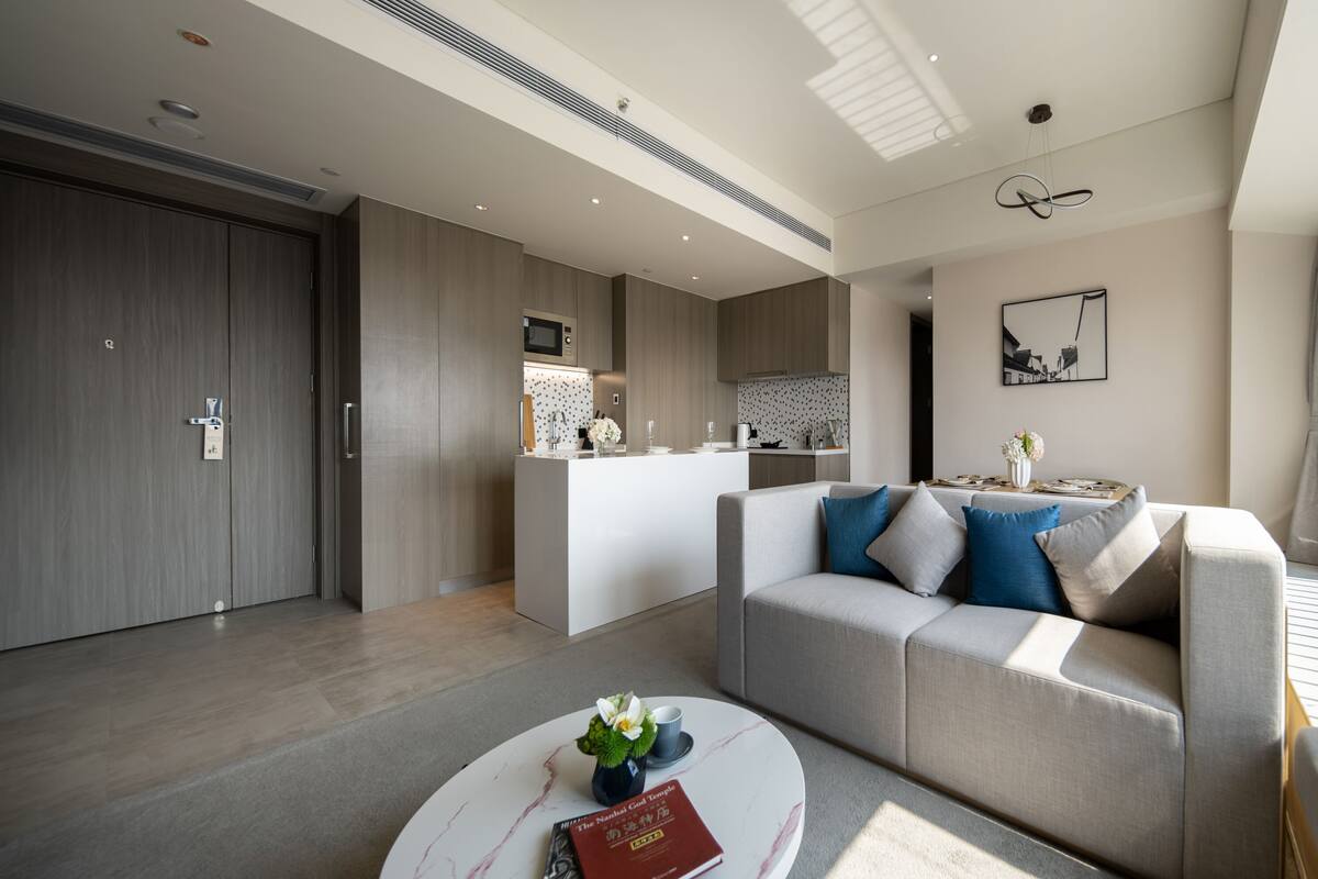 Un salon moderne avec un canapé, une table basse et un coin cuisine à l’arrière-plan.