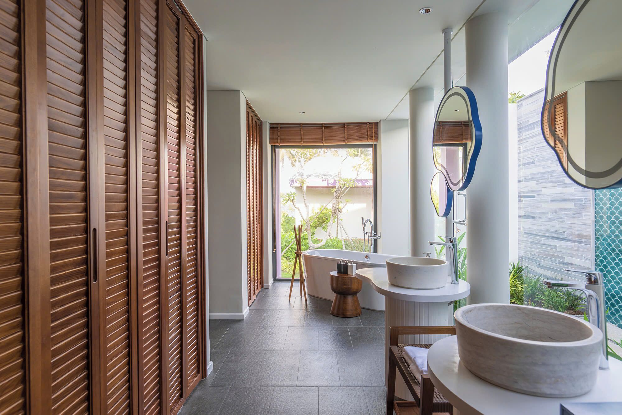 A modern bathroom with a large bathtub, a round sink, and a mirror.