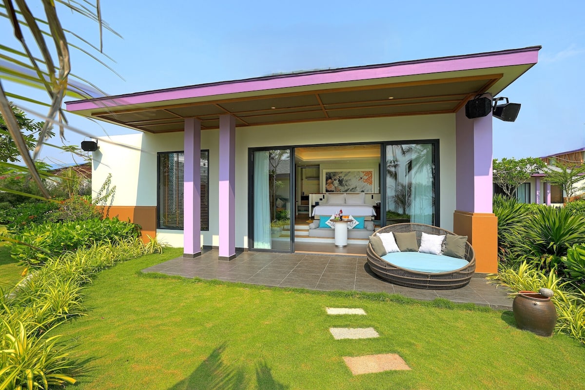 A modern house with a covered patio, a circular seating area, and a well-maintained garden.
