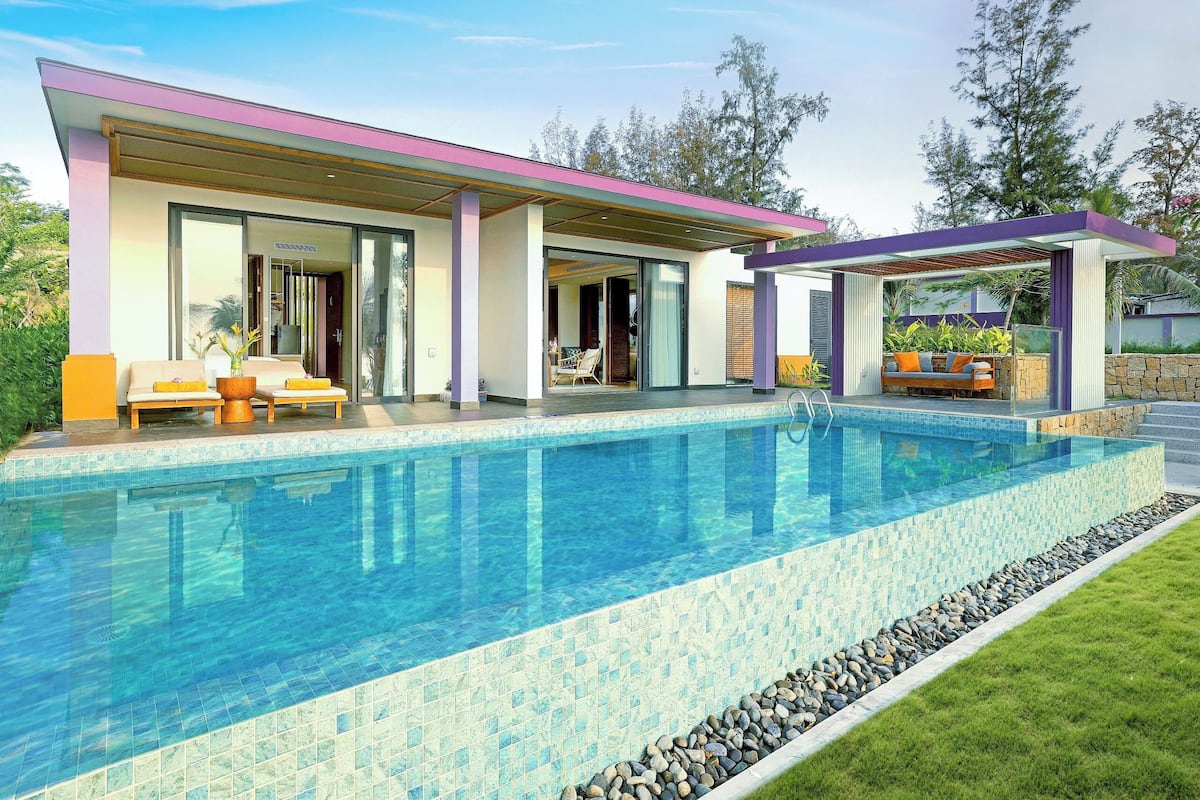 A modern house with a swimming pool, covered patio, and outdoor seating area.