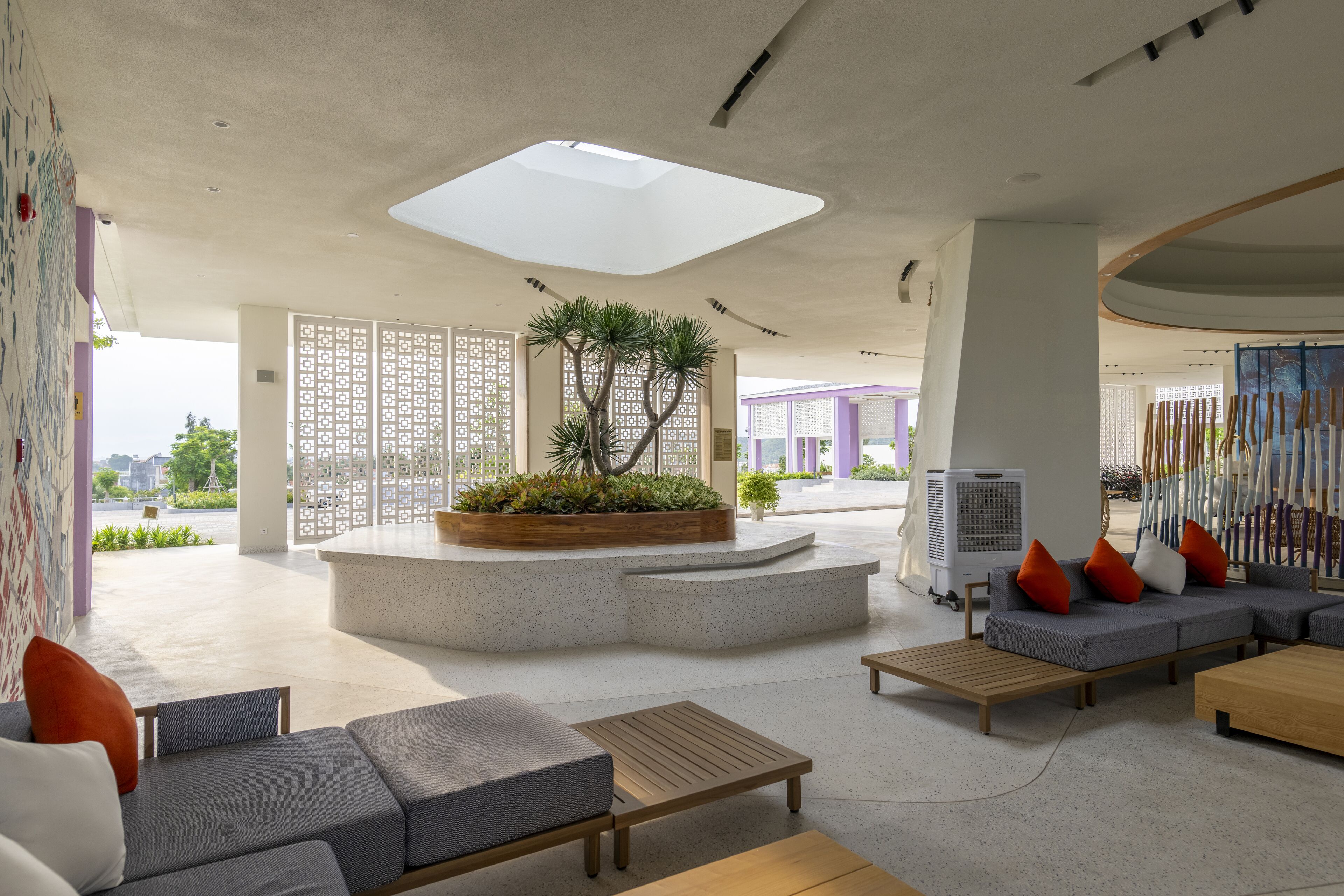 A modern lobby with a central planter, seating areas, and a large skylight.