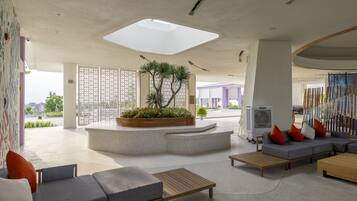 A modern lobby with a central planter, seating areas, and a large skylight.