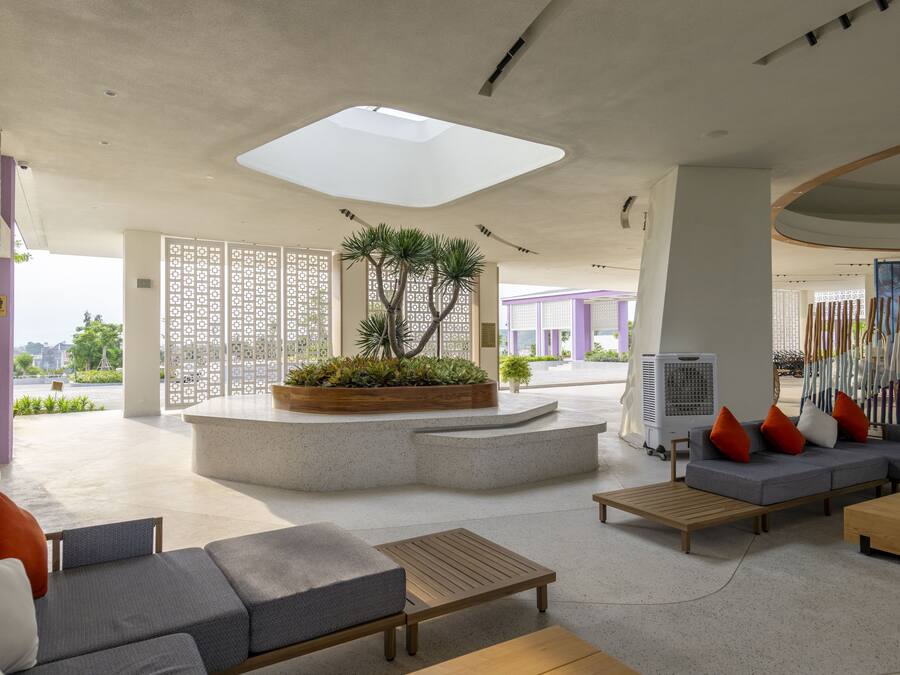 A modern lobby with a central planter, seating areas, and a large skylight.