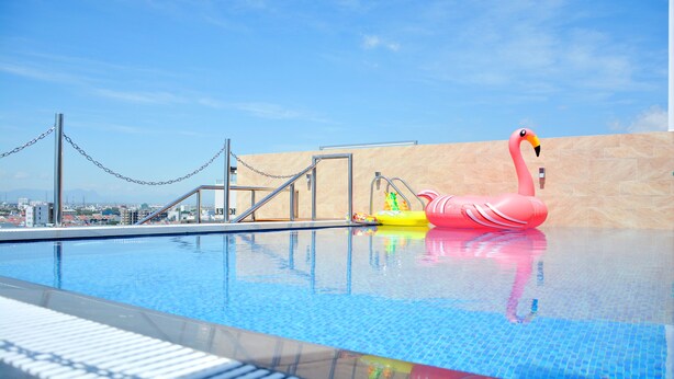 A swimming pool with a pink flamingo float and a yellow inflatable toy. - Richico Luxury Apartel Ocean (Da Nang)