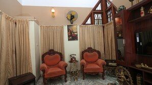 A room with two ornate chairs, a fan, a radio, and a decorative shelf. - "NALINAM HOME STAY"  with Bed & Breakfast , Near to Sri Padmanabha Swamy Temple. (Thiruvananthapuram)