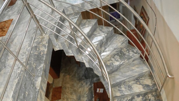A spiral staircase with marble steps and metal railings. - "NALINAM HOME STAY"  with Bed & Breakfast , Near to Sri Padmanabha Swamy Temple. (Thiruvananthapuram)