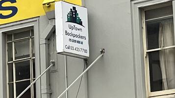 A sign for 'UpTown Backpackers' with a contact number.