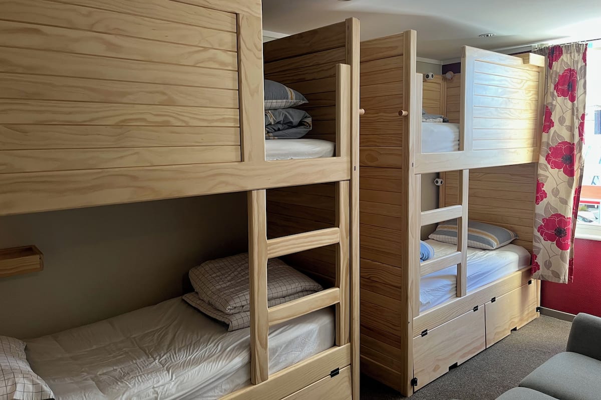Une chambre avec des lits superposés, des armoires en bois et un petit coin salon.