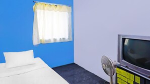 A room with a bed, a television, and a fan.