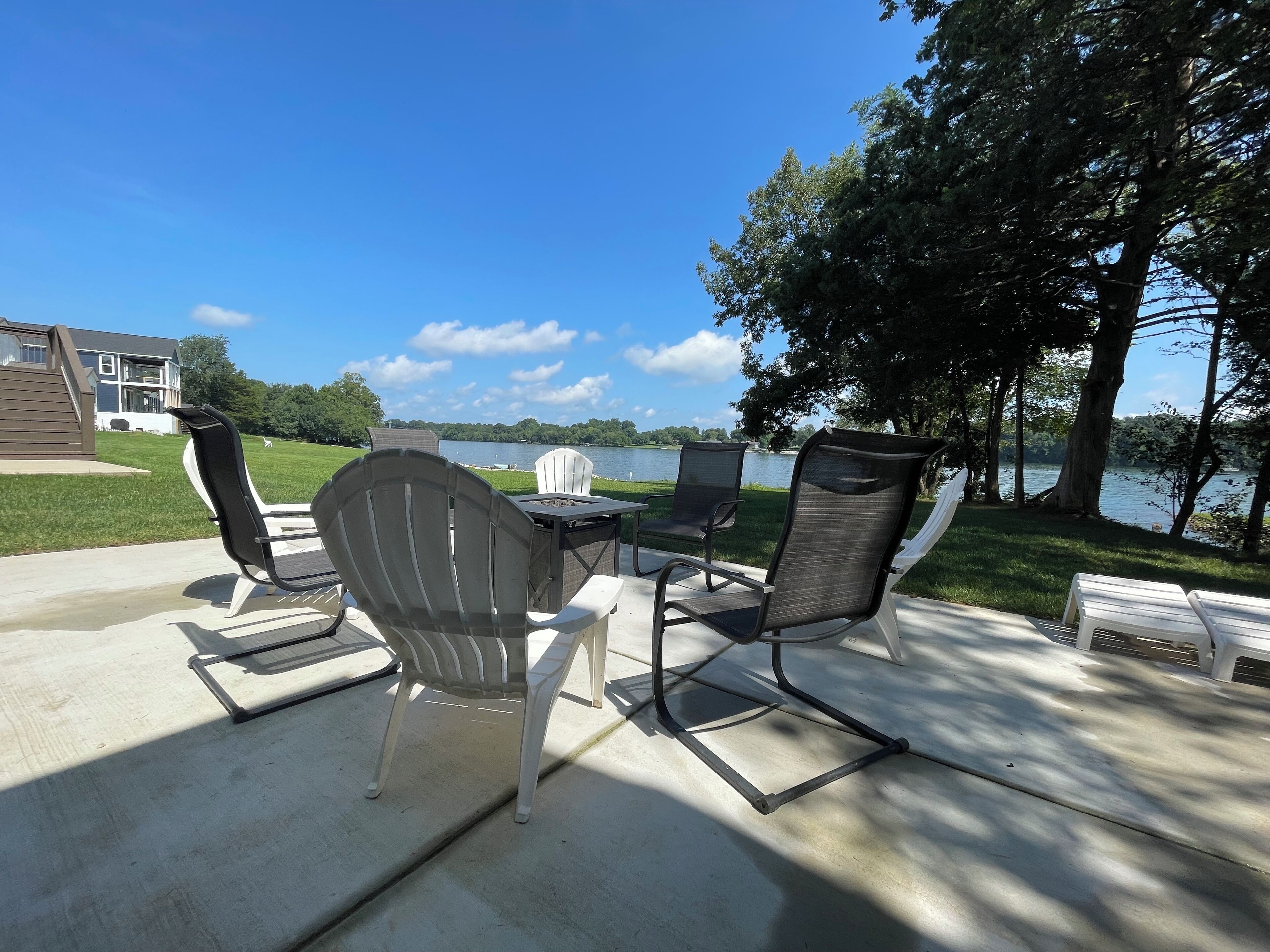 An outdoor patio with a table and chairs, overlooking a lake.