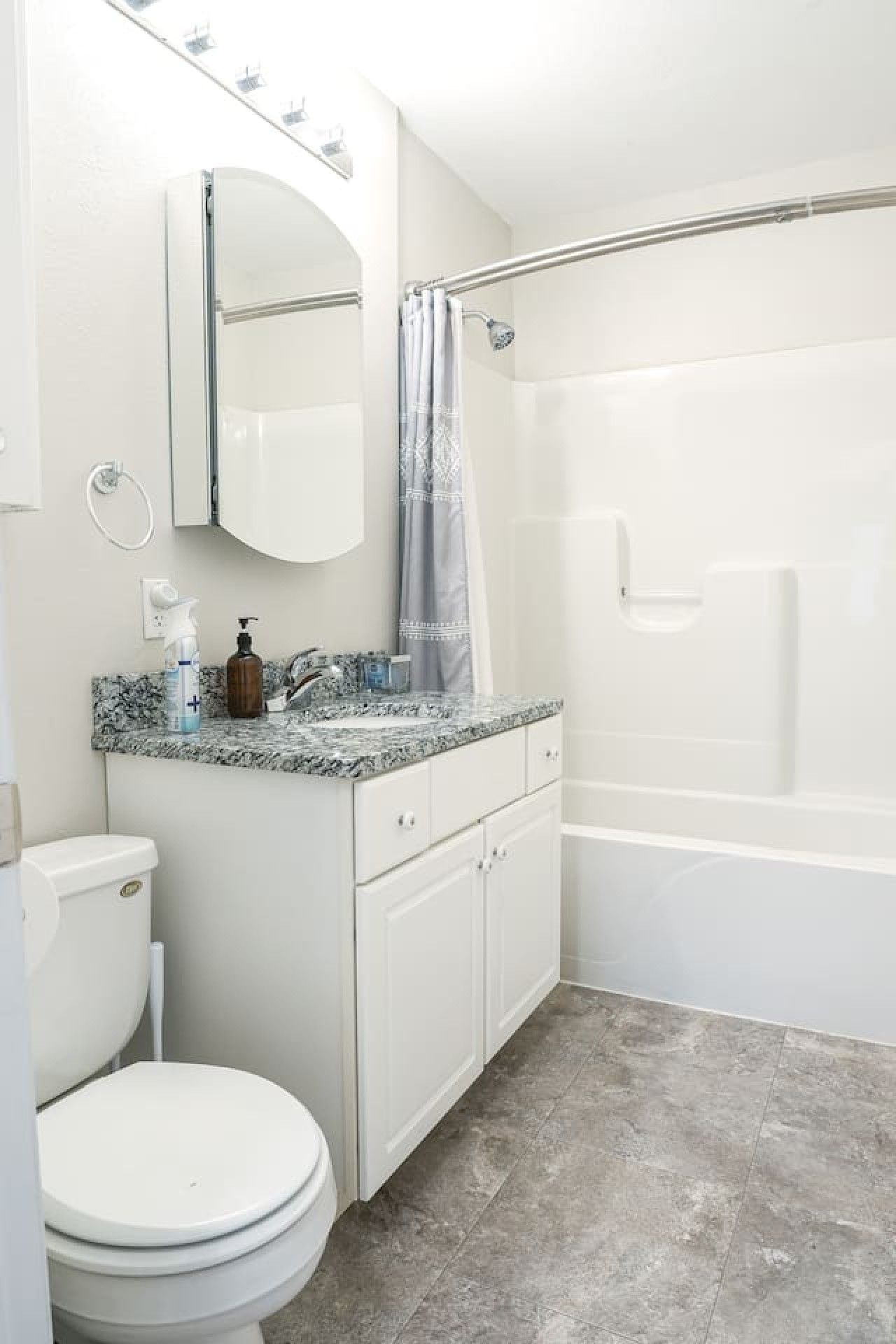 A bathroom with a toilet, sink, mirror, shower curtain, and bathtub.