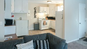 A compact living space with a kitchenette, a grey sofa, and a white door.
