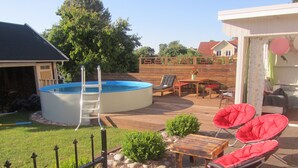 Un jardin avec une piscine, un barbecue, du mobilier d’extérieur et une terrasse en bois.