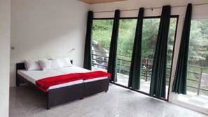 A modern bedroom with a bed, large windows, and a balcony. - Phulwari Resort (Ukhimath)
