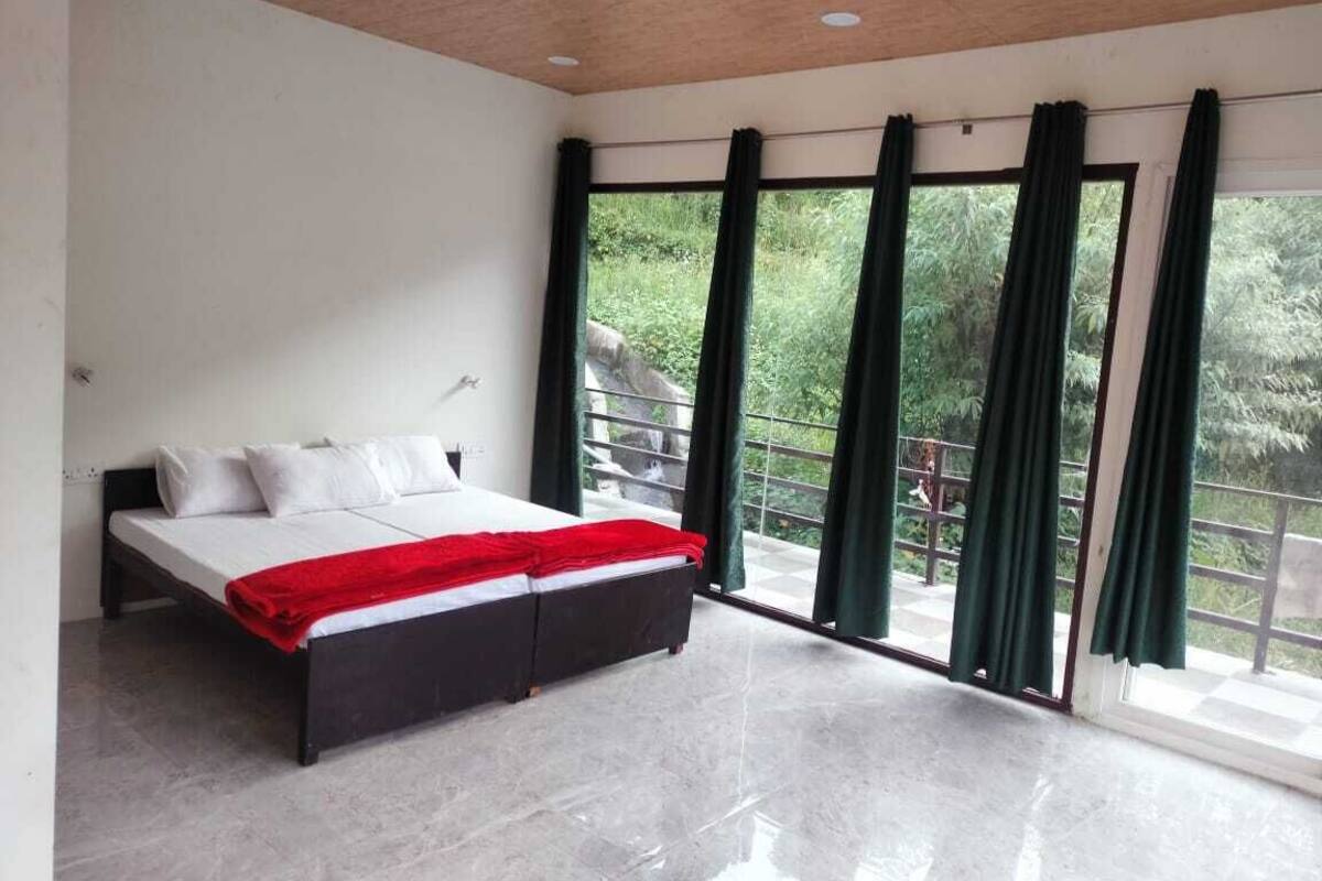 A modern bedroom with a bed, large windows, and a balcony.