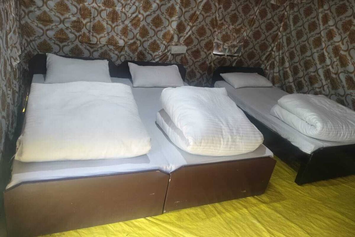 A room with a bed, two bedside tables, and patterned wallpaper.