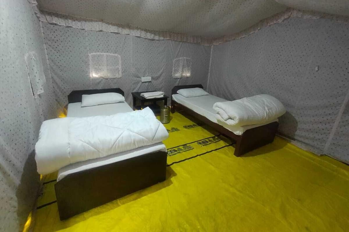 A room with three beds, a small table, and a yellow floor.