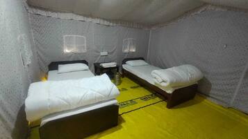 A room with three beds, a small table, and a yellow floor.