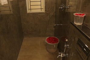 Une salle de bain avec un mur en marbre, une douche et des toilettes avec une poubelle.