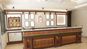 Un comptoir d’accueil agrémenté d’un panneau décoratif, d’une œuvre d  ’art encadrée et d’un symbole représentant une couronne.