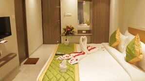 Une chambre d’hôtel avec un lit, une télévision, un miroir et un vase à fleurs.