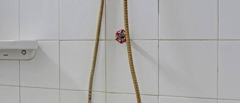 A shower with a gold hose and a handheld showerhead mounted on a tiled wall.