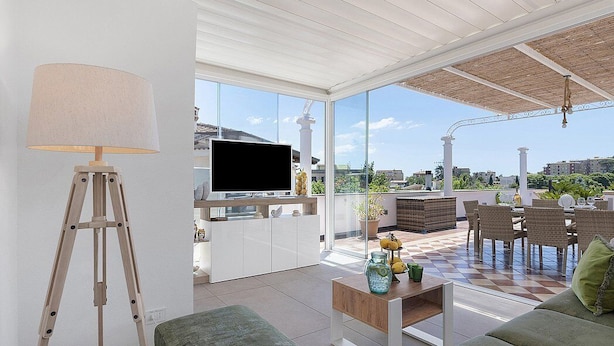 En moderne stue med et fjernsyn, et stativ, en sofa, et sofabord og et spiseområde med stole og et bord.