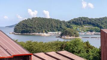 A coastal view with a forested island, a pier, and a building with a sign.