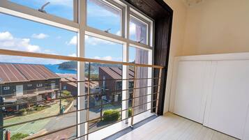 A room with a large window overlooking a residential area and a body of water.