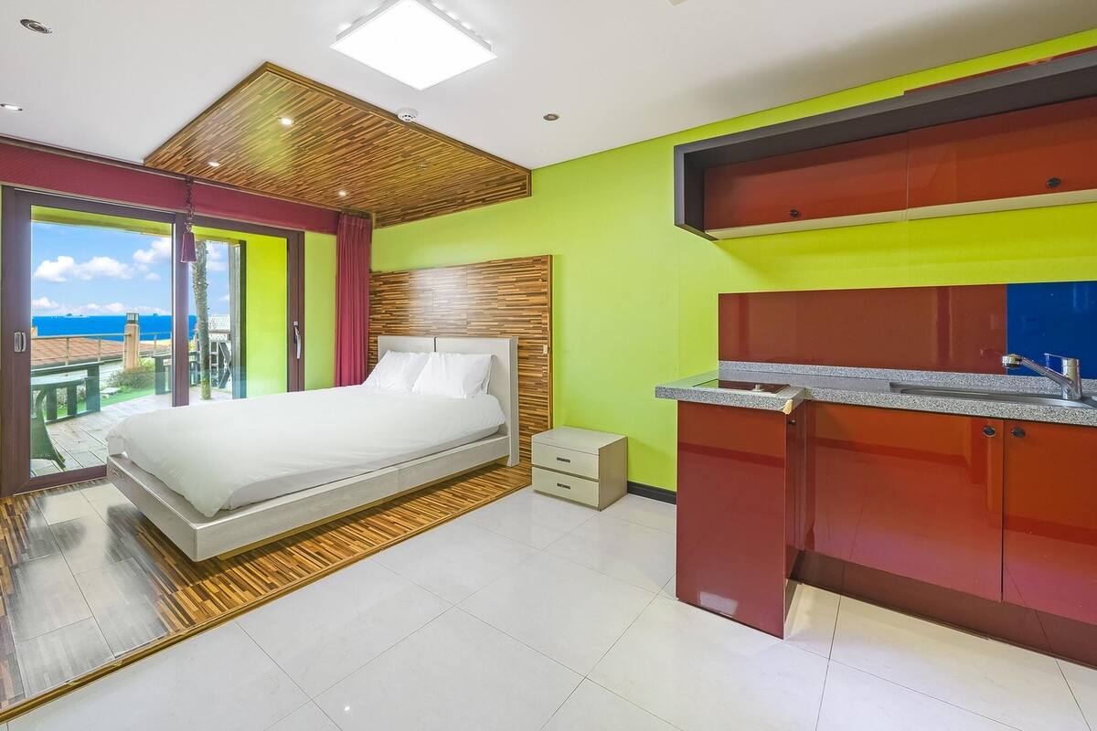 A modern hotel room with a large bed, a bathroom with a vanity, and a balcony with a view.