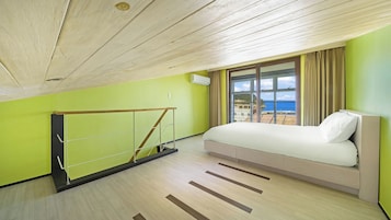 Un dormitorio con cama, ventana con vista, techo de madera y pared verde.