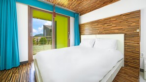 A modern hotel room with a large bed, wooden panel wall, and a sliding glass door leading to a balcony. - Geojedo Pilos Ocean View Pension (Geoje)
