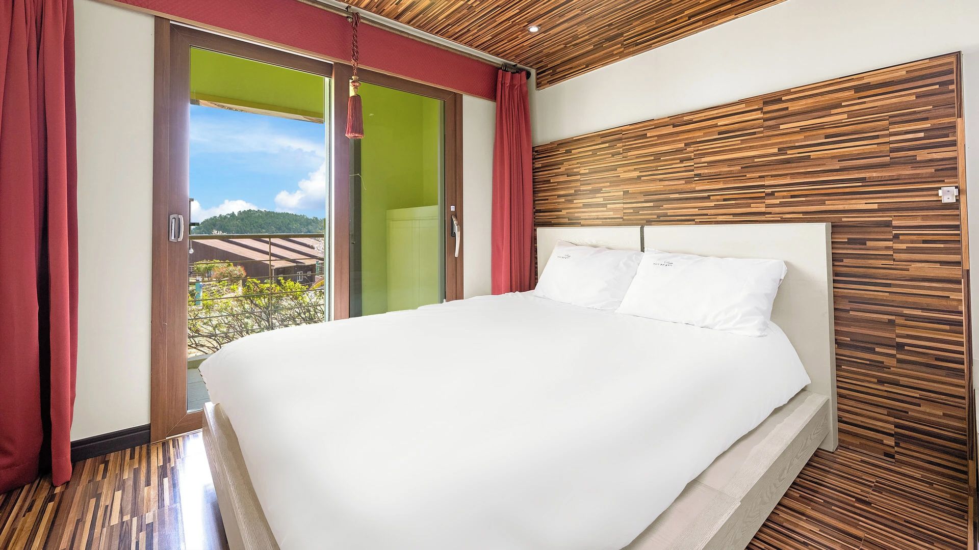 A bedroom with a large bed, wooden headboard, and a sliding glass door leading to a balcony.