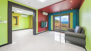 Une chambre d’hôtel moderne avec balcon, canapé et vue sur la mer.