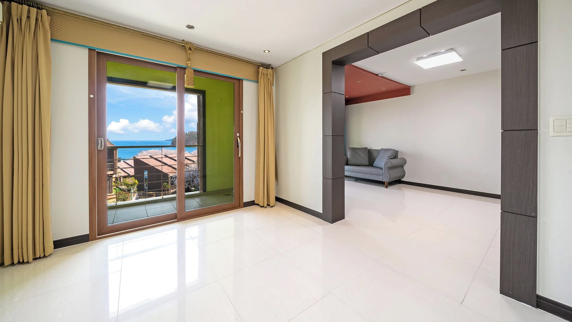 A modern interior with a balcony, a sofa, and a view of the sea.