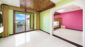 A room with a sliding glass door leading to an outdoor deck, a bed with a wooden headboard, and a bright pink accent wall.