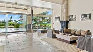 A spacious living area with a large glass door leading to a pool, comfortable seating, and a stone pillar.