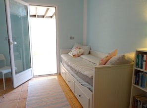 A bedroom with a bed, a bookshelf, and a sliding glass door leading to a balcony. - Casa Mimosa - Altea, Costa Blanca (Altea)