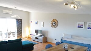 Ein modernes Wohnzimmer mit einer Couch, einem Fernseher, einem Holztisch und einem Essbereich.