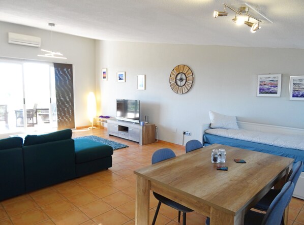 A modern living room with a sofa, a TV, a wooden table, and a dining area. - Casa Mimosa - Altea, Costa Blanca (Altea)