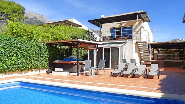Ein modernes Haus mit Swimmingpool, Sitzgelegenheiten im Freien und einer überdachten Terrasse.