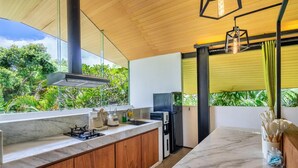 Una cocina moderna con encimera de mármol, armarios de madera, estufa a gas, horno empotrado y refrigerador.