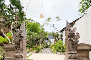 Traditional entrance with intricately carved pillars and lush greenery.