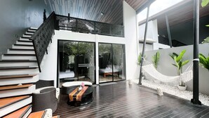A modern outdoor living area with a wooden deck, a hammock, and a seating area with a table and chairs. - Exclusive Villa F3 with Jacuzzi - MANA VILLAS (Benoa)