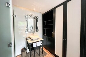 Ein modernes Badezimmer mit einem großen Spiegel, einem Waschbecken und einem schwarzen Schrank.