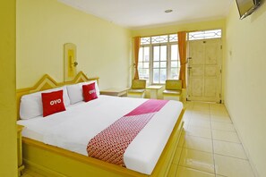 A hotel room with a bed, a desk, a chair, and a window with curtains. - OYO 3722 Hotel Mutiara (Purwokerto)